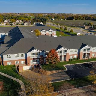 Aerial view of a suburban apartment complex with surrounding greenery and a parking lot.