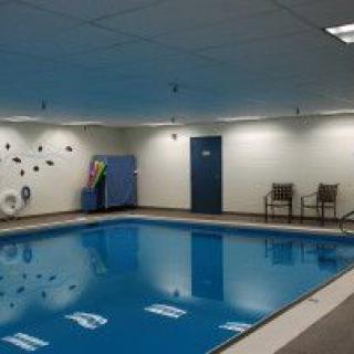 An indoor swimming pool with chairs and a lifebuoy mounted on the wall.