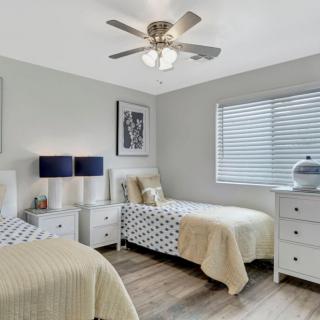 A modern bedroom with two twin beds and neutral decor.