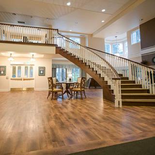 A spacious interior lobby with a grand staircase and wooden flooring.