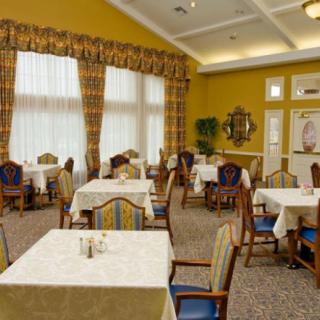 An empty dining room with neatly arranged tables and chairs, featuring large windows with curtains.