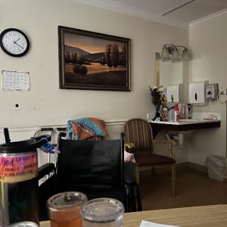 A cozy hospital room featuring a painting, a clock, and various pieces of furniture.
