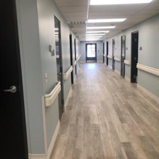 A well-lit hallway in a healthcare facility, featuring multiple doors and modern flooring.