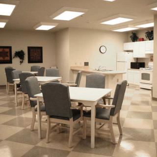 A communal kitchen and dining area with tables, chairs, and appliances.