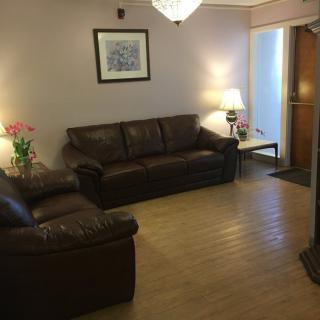 A cozy living room with leather sofas, a lamp, and decorative flowers.