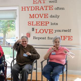 Seniors participating in a wellness activity at a community center, with motivational words on the wall.