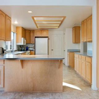 A modern kitchen with wooden cabinets and an island under bright lighting.