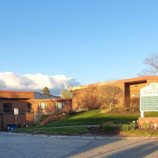 A view of the school campus with a clear sky and sunlight illuminating the surroundings.