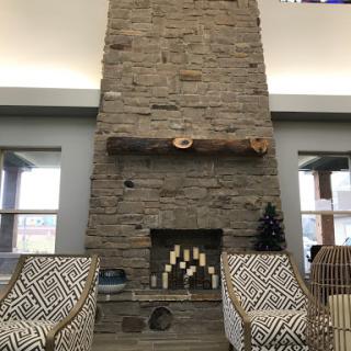 A cozy and modern living room featuring a tall stone fireplace as the focal point.