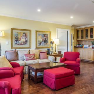A cozy living room featuring red furniture, artwork, and warm lighting.