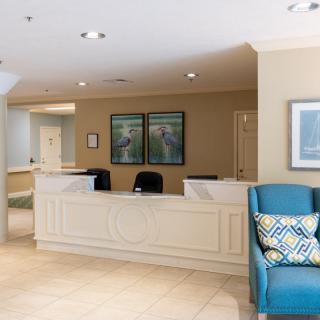 A reception area featuring a desk, chairs, and wall art in a well-lit office lobby.