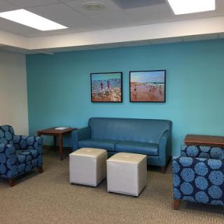 A modern waiting area featuring comfortable furniture and vibrant blue walls.