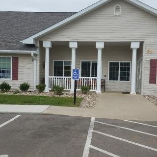 A single-story building with a front porch, columns, and an accessible parking space in front.