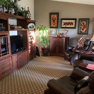 A cozy living room featuring wooden furniture, artwork, and a touch of greenery.