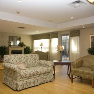 A cozy living room with a patterned sofa, armchair, coffee table, and fireplace.