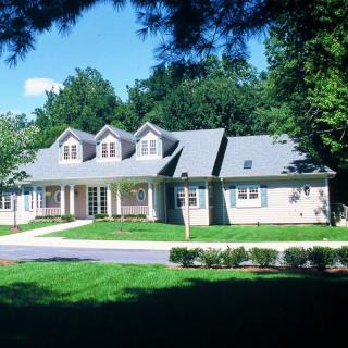 A suburban residential house surrounded by a manicured lawn and trees.