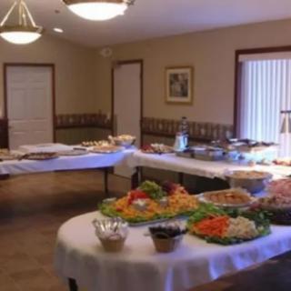 A buffet setup in a well-lit room, featuring a variety of dishes displayed on tables.