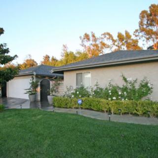 A suburban house with a well-maintained garden and lawn in the foreground.