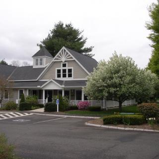 A charming residential building with a neatly landscaped yard and driveway.