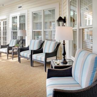 A comfortable outdoor porch with cushioned chairs and lamps, ideal for relaxation.