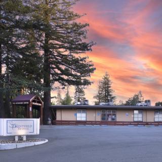 A school building with a beautiful sunset sky in the background, surrounded by tall trees.