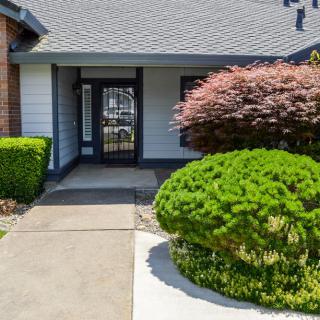 A welcoming house entrance with neatly trimmed shrubs and a paved pathway.