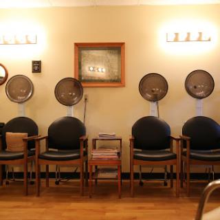 A cozy salon waiting area with comfortable chairs and vintage hair dryers.