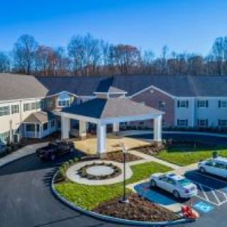 Aerial view of a residential building with a driveway and parked cars.