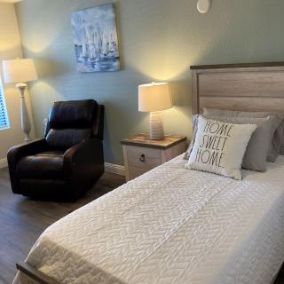 A cozy bedroom with a single bed, armchair, and soft lighting.