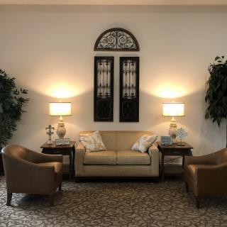 A cozy living room setup with a sofa, two chairs, lamps, and decorative plants.