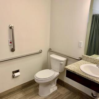 A clean and accessible bathroom featuring a toilet, sink, and grab bars for support.