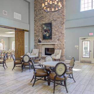 A spacious lounge featuring a stone fireplace and elegant seating arrangements under a large chandelier.