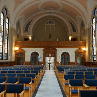 A serene interior view of a church with rows of blue chairs and elegant architecture.