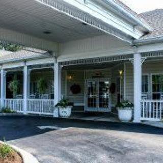 Entrance of a building with a covered porch and decorative columns.