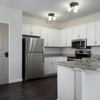 A modern kitchen with white cabinets and stainless steel appliances.