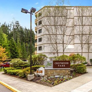 An apartment building surrounded by trees and greenery with a welcoming sign at the entrance.