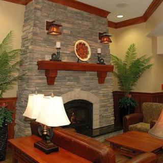 A cozy living room featuring a stone fireplace, mantel with decorative items, and ambient lighting.