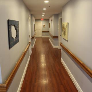 A long hallway with artwork and wooden floors, typical of a hospital or nursing home.