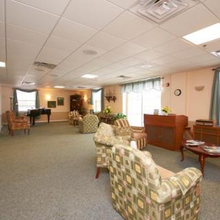 A spacious living room with multiple seating areas and a piano, decorated in neutral tones.