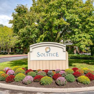 Entrance sign of Solstice surrounded by colorful flowers and greenery.