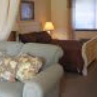 A cozy living space with a comfy sofa, decorative cushions, and a bed in the background.