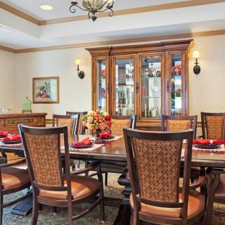 A beautifully designed dining room with a large table, chairs, and an elegant cabinet in the background.