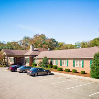 A well-maintained commercial building with a spacious parking lot surrounded by greenery.