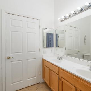 A clean and bright bathroom with a double sink vanity, large mirrors, and overhead lighting.