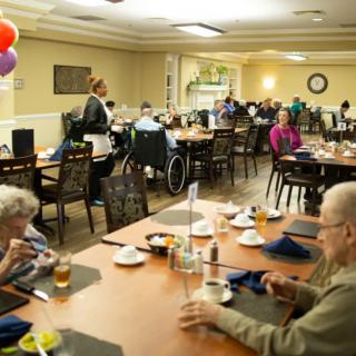 Elderly individuals enjoying a meal together in a nursing home dining room.