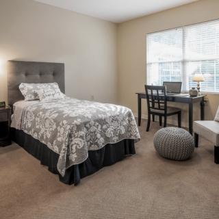 A cozy bedroom with a single bed, desk, and window allowing natural light.
