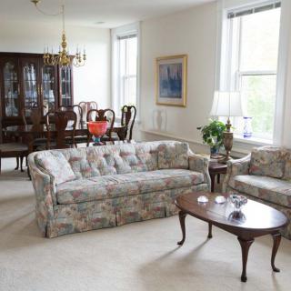 A bright living and dining area featuring a floral sofa set and a wooden dining table with chairs.