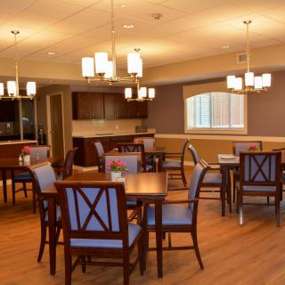 A cozy dining area with wooden tables and chairs, soft lighting, and a warm ambiance.