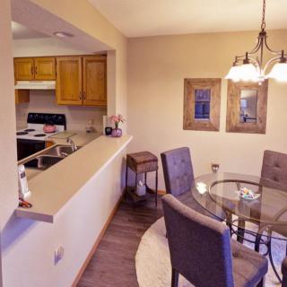 A cozy dining area with a glass table and cushioned chairs adjacent to a kitchen space.