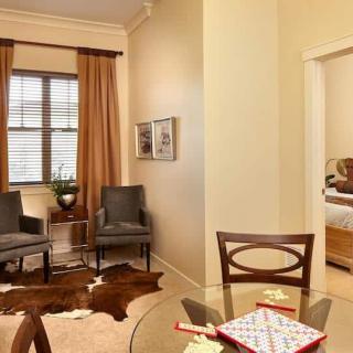 A cozy living area featuring a seating space with two armchairs, a glass table set for board games, and decorative artwork on the wall.